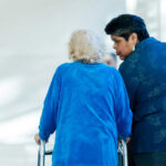 Elderly stroke patient walks with a health care professional