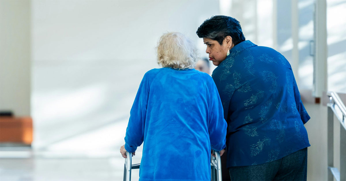 Elderly stroke patient walks with a health care professional