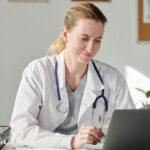 A female clinician makes notes during a virtual call