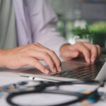 An unidentified general practitioner uses their laptop computer to make an eReferral for a patient