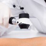A GP uses a dermatoscope to assess patient's arm for signs of skin cancer